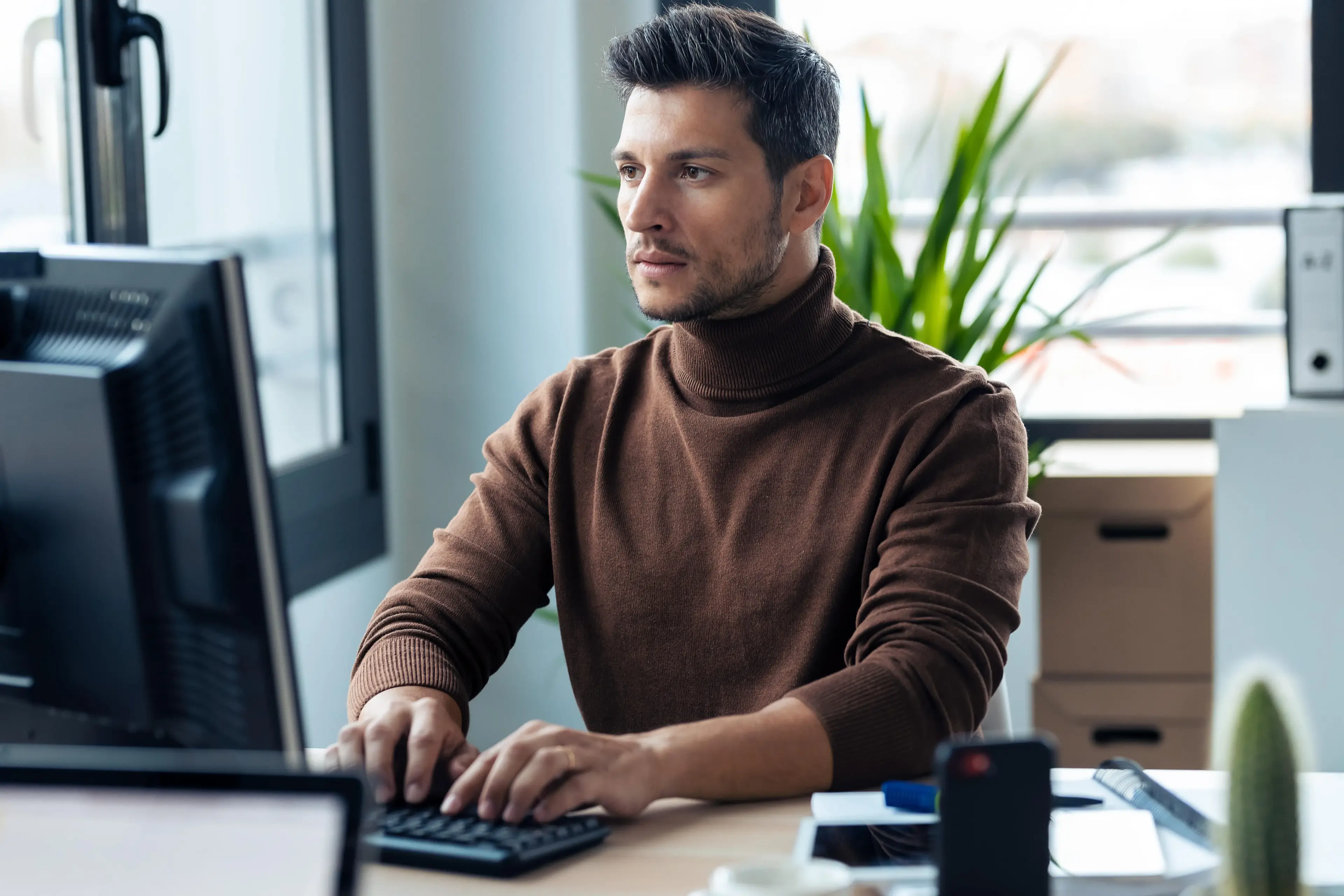Man working at a computer in a modern office setting.